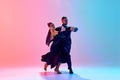 Beautiful young man and handsome woman, ballroom dancers making performance, dancing against gradient pink blue Royalty Free Stock Photo