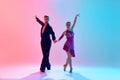 Beautiful young man and handsome woman, ballroom dancers making performance, dancing against gradient pink blue Royalty Free Stock Photo