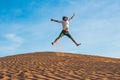 Beautiful young man jumping barefoot on sand in desert enjoying nature and the sun. Fun, joy and freedom Royalty Free Stock Photo