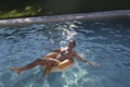 Beautiful young man in swimware floating in a pool at sunset