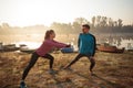 Beautiful young man and woman exercising, stretching in the early morning mist on the lake or river banks Royalty Free Stock Photo