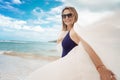 Beautiful young mature woman smiles joyfully in sunglasses in a swimsuit with a white scarf on a tropical paradise beach Royalty Free Stock Photo