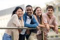 Beautiful young men and women smiling and looking at camera leaning on a balcony. Diverse group of cheerful and hopeful Royalty Free Stock Photo