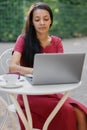 beautiful and young millennial african woman in a public place working on a laptop