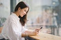 Beautiful young millennial Asian woman using a smartphone at a cafe. Portrait of a gorgeous smiling female engrossed in Royalty Free Stock Photo