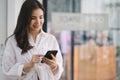 Beautiful young millennial Asian woman using a smartphone at a cafe. Portrait of a gorgeous smiling female engrossed in Royalty Free Stock Photo