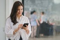 Beautiful young millennial Asian woman using a smartphone at a cafe. Portrait of a gorgeous smiling female engrossed in Royalty Free Stock Photo