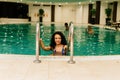 Beautiful young mixed race African American woman, wearing bikini and relaxing on a swimming pool Royalty Free Stock Photo