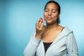 Beautiful young mixed race woman in casual clothing eating and enjoying a fresh strawberry with a blue background Royalty Free Stock Photo