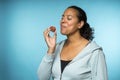 Beautiful young mixed race woman in casual clothing eating and enjoying a fresh strawberry with a blue background Royalty Free Stock Photo