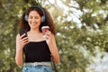 Beautiful young mixed race woman listening to music and texting on her phone outside. Confident and happy african Royalty Free Stock Photo