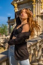 Beautiful young model with long blonde hair in blue jeans and a black top standing dancing on a towering staircase with her arms Royalty Free Stock Photo