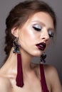 Beautiful young model with professional makeup, perfect skin, long earrings, dark lips