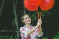 Beautiful young model smiling with red ballons in the garden Royalty Free Stock Photo