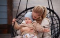 Beautiful Young Mom and baby hugging and have fun. Mother holding her son. Models wearing knitted beige sweater, jacket, beanie