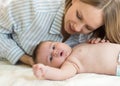 Beautiful young mother looking at her baby son and smiling, lying in bed at home Royalty Free Stock Photo