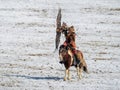 Beautiful young Mongolian golden eagle hunter on horseback releases her eagle into the wild, a dynamic hunting scene with an eagle