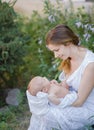 A beautiful young mother with a baby in her arms is standing in the garden. Royalty Free Stock Photo