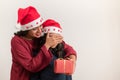Beautiful young mother covering eyes of her daughter giving a present christmas on white background with copy space for text Royalty Free Stock Photo