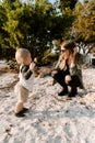 Beautiful Young Mother and Cute Little Boy Son Walking and Enjoying the Nice Outdoor Weather on the Sandy Beach next to the Ocean Royalty Free Stock Photo