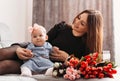 Beautiful young mother with daughter baby on the bed with flowers. Congratulations on Mother`s Day