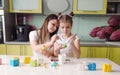 Beautiful young mother and daughter paint Easter eggs at home in the kitchen Royalty Free Stock Photo