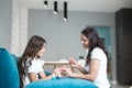 Beautiful young mother doing manicure to her cute smiling teen daughter applying nail polish both having fun at home Royalty Free Stock Photo