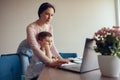 Beautiful young mother helping little son schoolboy in online learning at laptop. Royalty Free Stock Photo