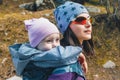 Young mother with her toddler daughter on back in ergonomic baby carrier outside in nature Royalty Free Stock Photo