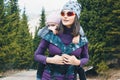 Young mother with her toddler daughter on back in ergonomic baby carrier outside in nature. Babywearing concept Royalty Free Stock Photo