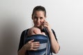 Mother with smartphone and baby sleeping in sling. Studio shot. Royalty Free Stock Photo