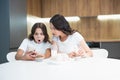 Beautiful young mother with her cute teenager daughter watching photoes on the phone while having cupcakes with milk for Royalty Free Stock Photo