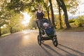 Beautiful young mother with her daughter in jogging stroller running outside in autumn nature Royalty Free Stock Photo