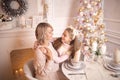 Beautiful young mother with her daughter in the New Year`s interior at the table near the Christmas tree Royalty Free Stock Photo