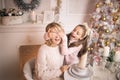 Beautiful young mother with her daughter in the New Year`s interior at the table near the Christmas tree Royalty Free Stock Photo