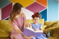 Beautiful young mother with her little cute daughter happily drawing in coloring book with felt-tip pens while spending