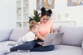 Young pretty mother and her little happy daughter are using a laptop and smiling while sitting on sofa at home Royalty Free Stock Photo