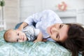 Beautiful young mother with her newborn baby son lying on bed in her bedroom. Royalty Free Stock Photo