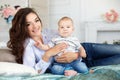 Beautiful young mother with her newborn baby son lying on bed in her bedroom. Royalty Free Stock Photo