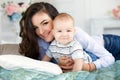 Beautiful young mother with her newborn baby son lying on bed in her bedroom. Royalty Free Stock Photo