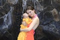 Beautiful young mother is holding baby girl outside near pool. Royalty Free Stock Photo