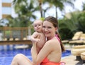 Beautiful young mother is holding baby girl outside near pool. Royalty Free Stock Photo