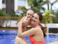 Beautiful young mother is holding baby girl outside near pool. Royalty Free Stock Photo