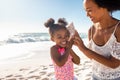 Cute little black girl listening to shell at beach with her mom Royalty Free Stock Photo