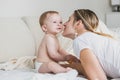 Beautiful young mother kissing baby boy in cheek on bed Royalty Free Stock Photo