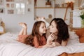 Happy cute little girl with a beautiful young mother lie on the bed Royalty Free Stock Photo