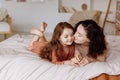 Happy cute little girl with a beautiful young mother lie on the bed Royalty Free Stock Photo