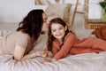 Happy cute little girl with a beautiful young mother lie on the bed Royalty Free Stock Photo