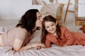 Happy cute little girl with a beautiful young mother lie on the bed Royalty Free Stock Photo