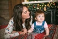 A beautiful young mother lies on the bed with her little daughter against the background of the Christmas fireplace. The woman Royalty Free Stock Photo